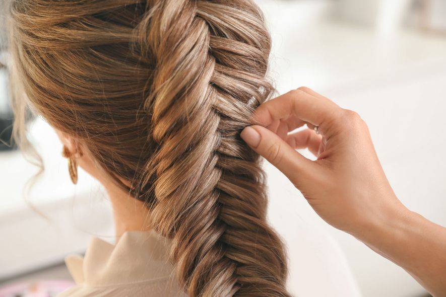 A woman is getting her hair braided by a hairdresser.