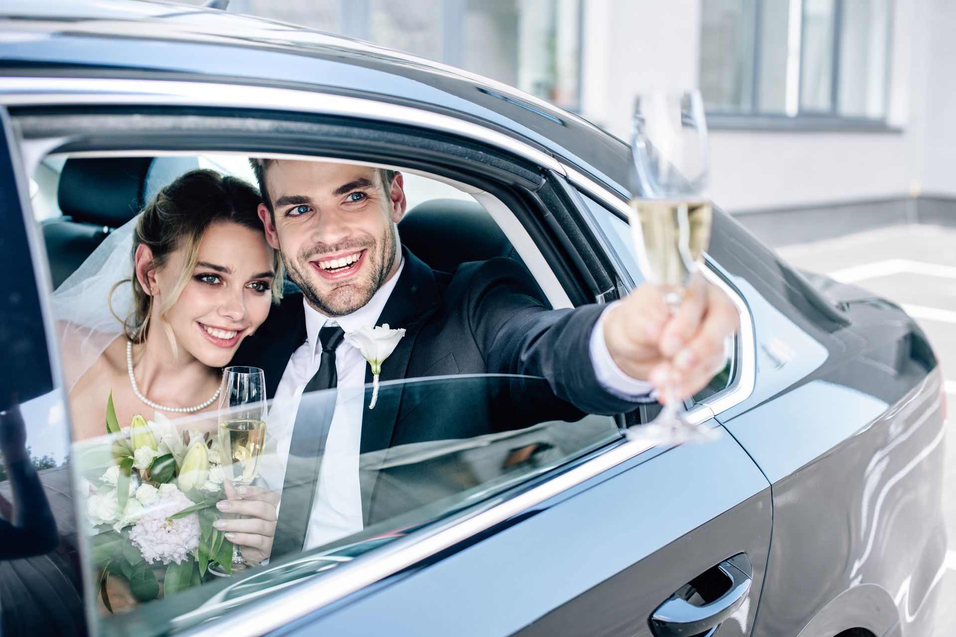 Attractive bride and handsome bridegroom smiling and holding champagne glasses.