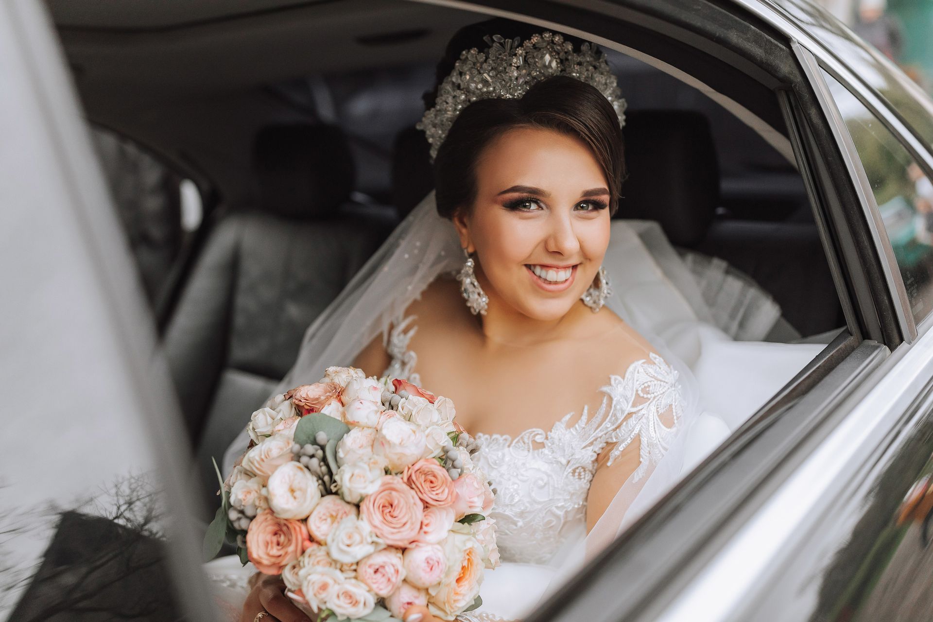 Portrait of a smiling bride in the car window, showcasing trusted wedding transportation services.