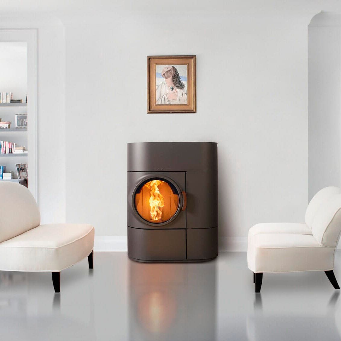 Moderna stufa con fuoco, quadri incorniciati e due sedie bianche in una stanza luminosa.