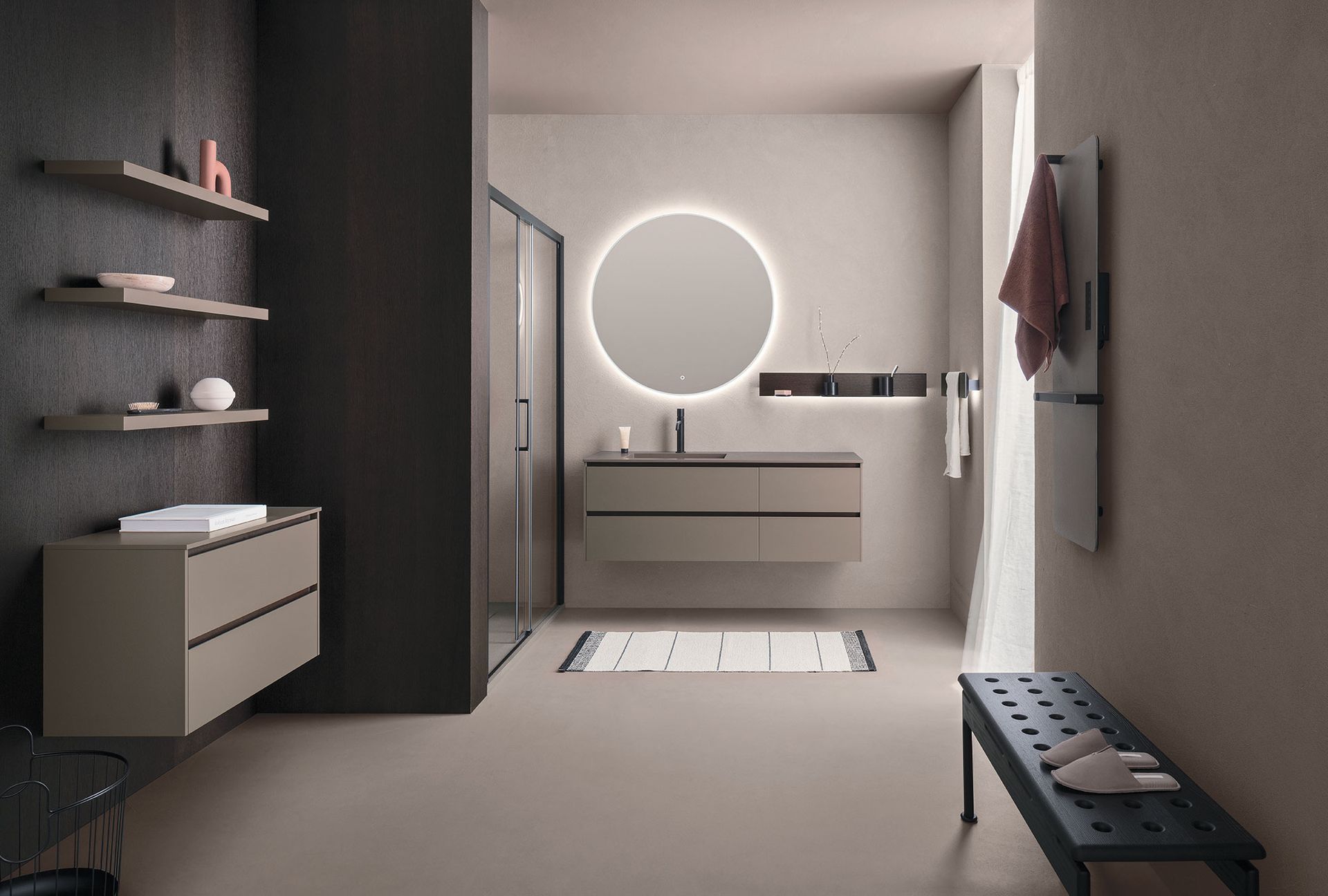 Bagno moderno con toni neutri, mobile lavabo sospeso, specchio rotondo e doccia aperta.