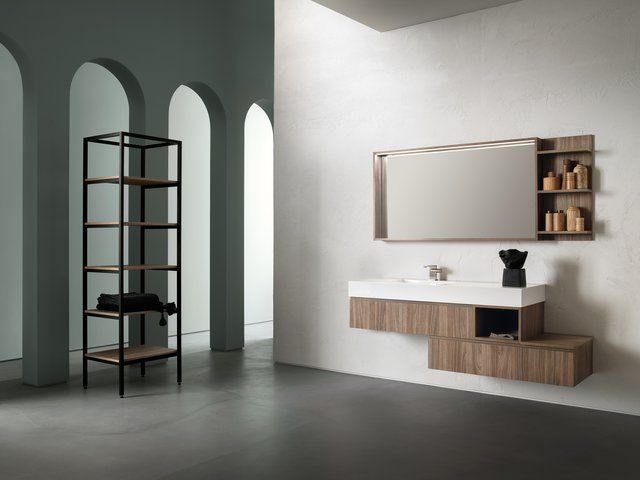 Bagno moderno con mobile lavabo sospeso, specchio e mensole. Sulla sinistra si trova un mobile contenitore in metallo e legno.