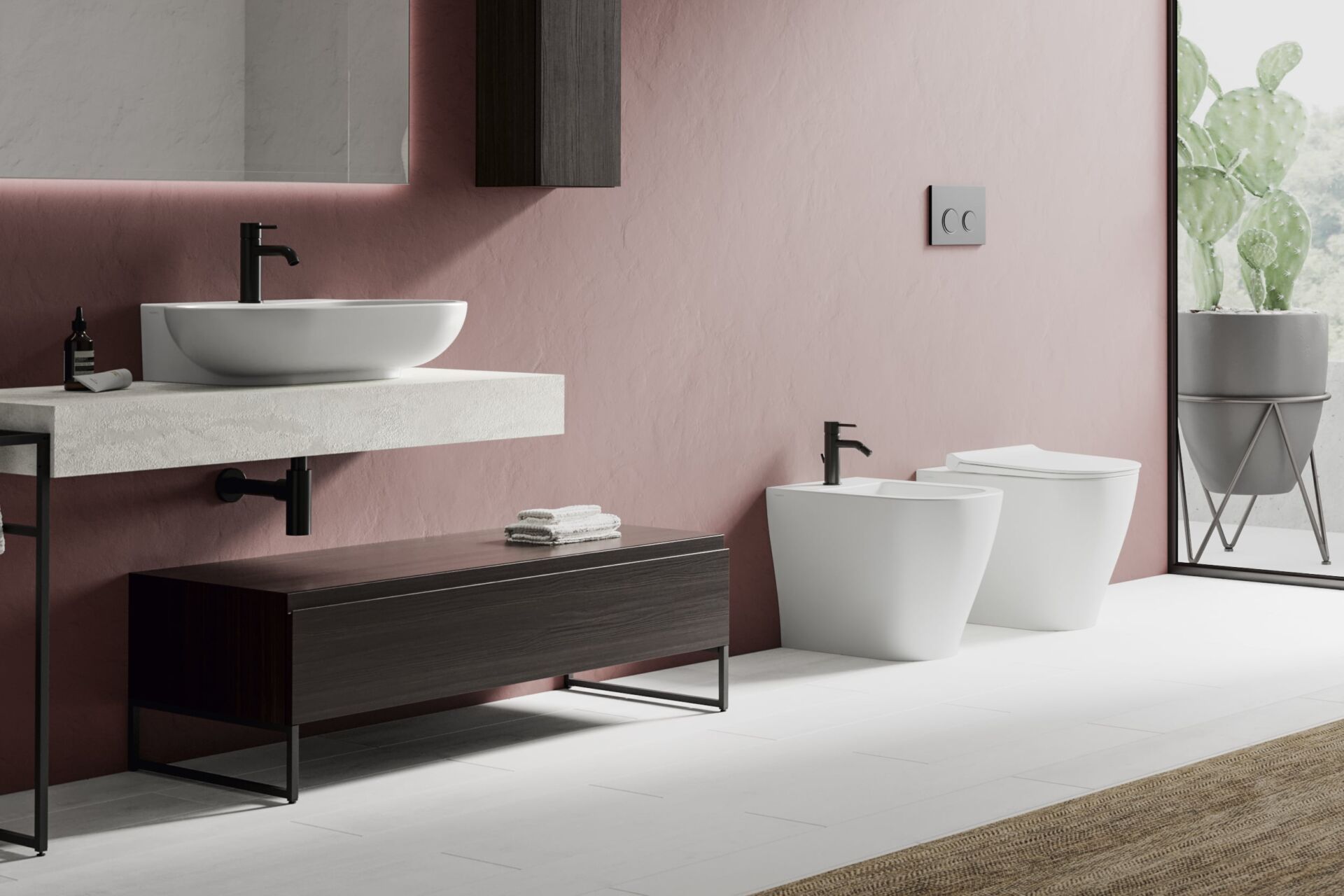 Bagno moderno con parete rosa, lavandino bianco e sanitari scuri.