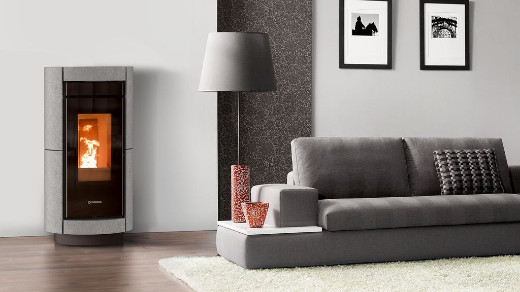 Stufa a pellet grigia in un soggiorno moderno con divano grigio e lampada da terra.