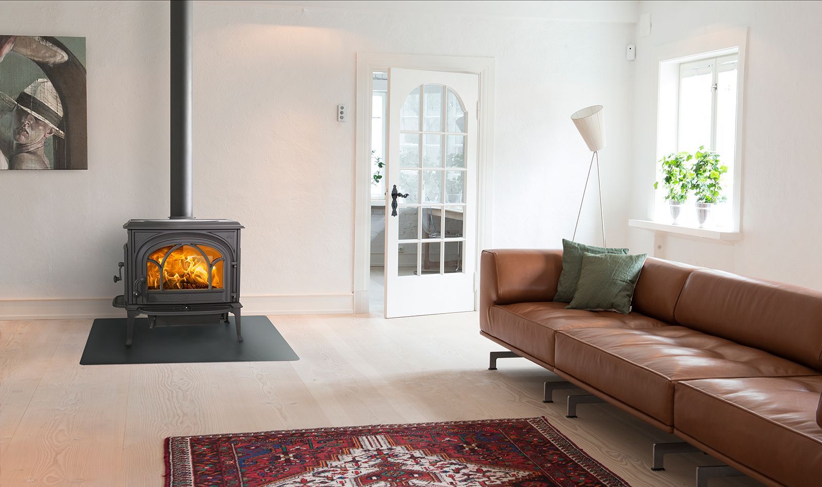 Accogliente soggiorno con camino acceso, divano in pelle, tappeto a fantasia e una porta che conduce a un'altra stanza.