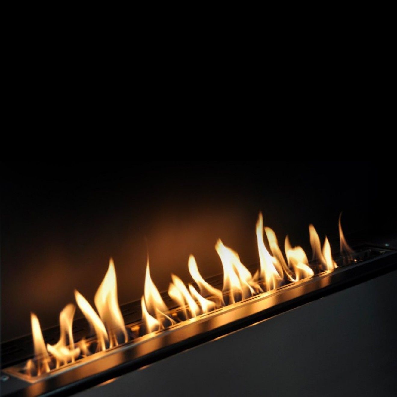 Fiamme in un camino rettangolare in metallo su uno sfondo scuro.