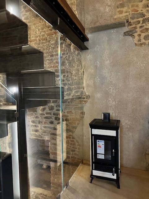 Scala con pannello in vetro, parete in pietra e stufa bianca e nera.