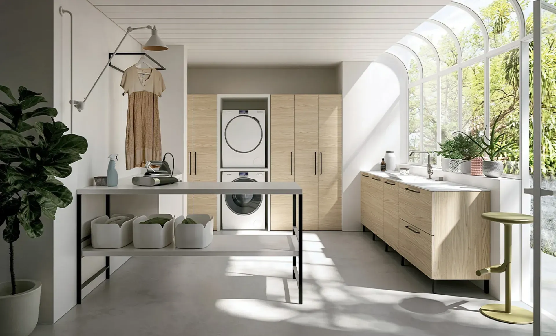 Moderna lavanderia con mobili in legno chiaro, colonna per lavatrice/asciugatrice e ampia finestra con verde.
