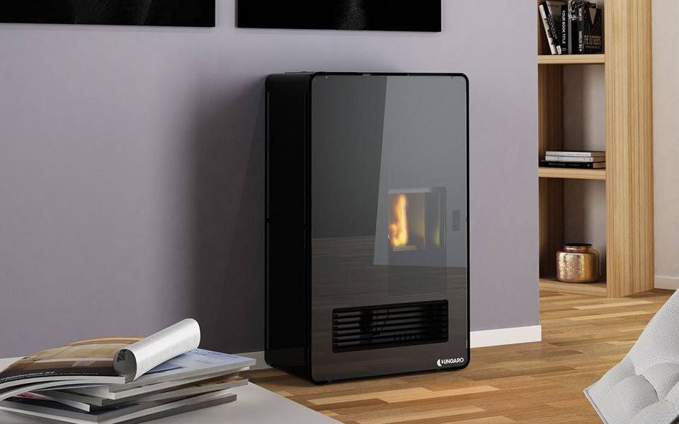 Stufa a pellet nera contro una parete viola, con una parte anteriore in vetro che mostra una fiamma, in un ambiente moderno.