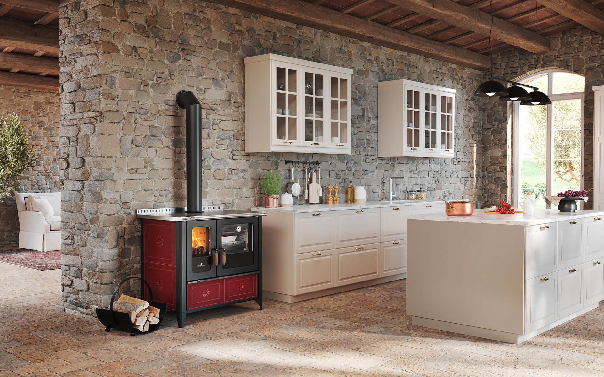 Cucina rustica con stufa rossa, mobili bianchi, isola, parete in pietra.