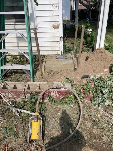 Construction site. Concrete slab, metal posts, ladder, and pump.