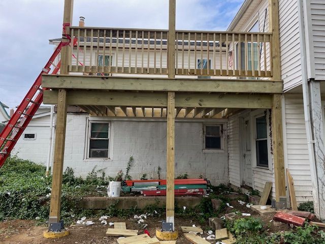Newly constructed wooden deck attached to a white house with a ladder.