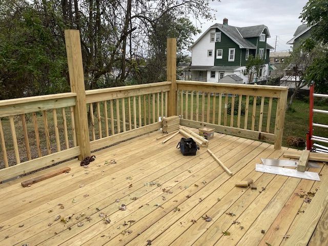 Newly constructed wooden deck with railing; building in progress, tools visible.