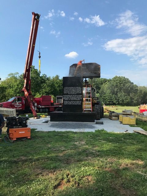 Construction site with a crane lifting dark blocks, building a structure on a concrete slab.