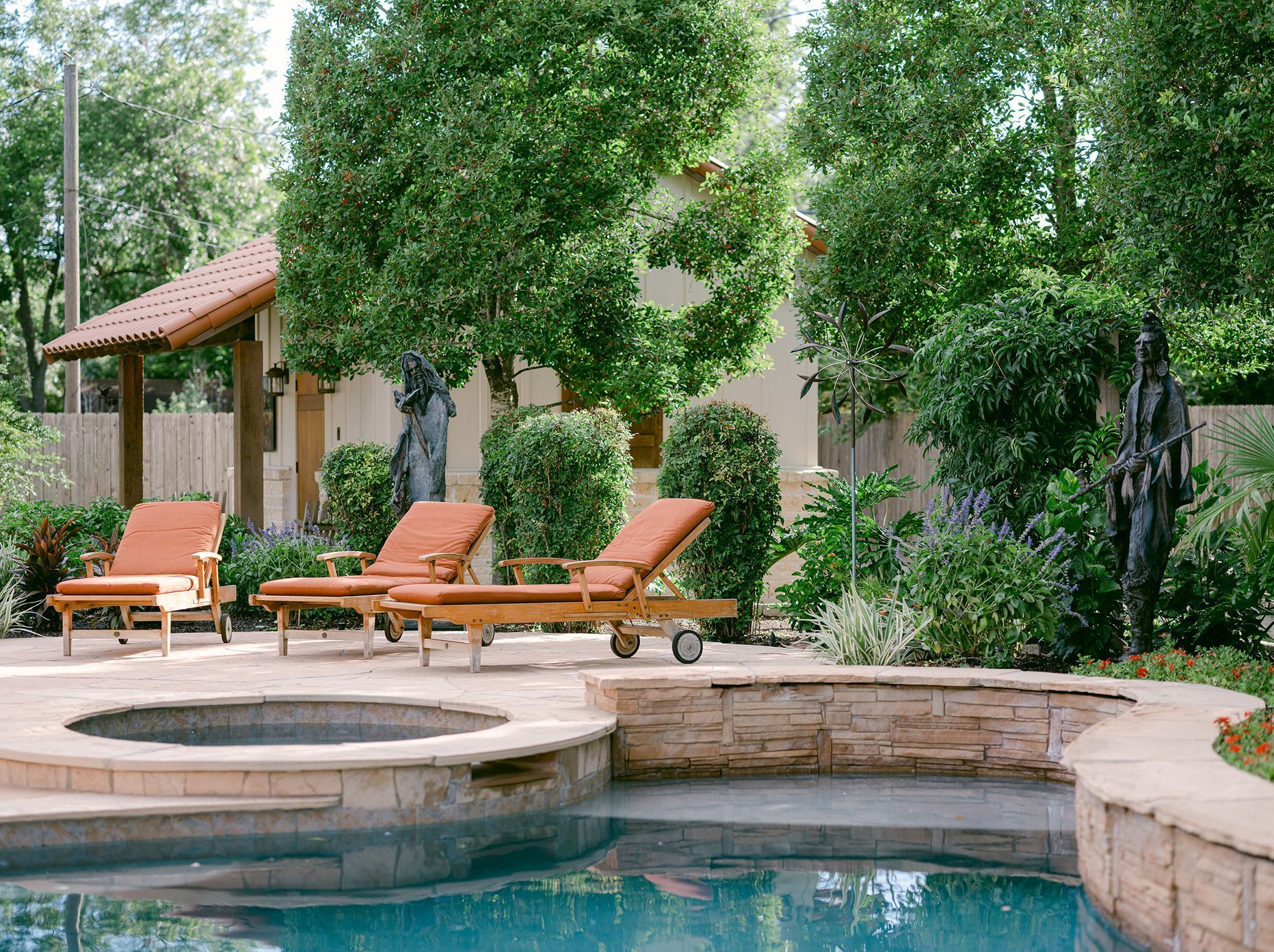 A swimming pool with lounge chairs and a hot tub in the backyard of a house.
