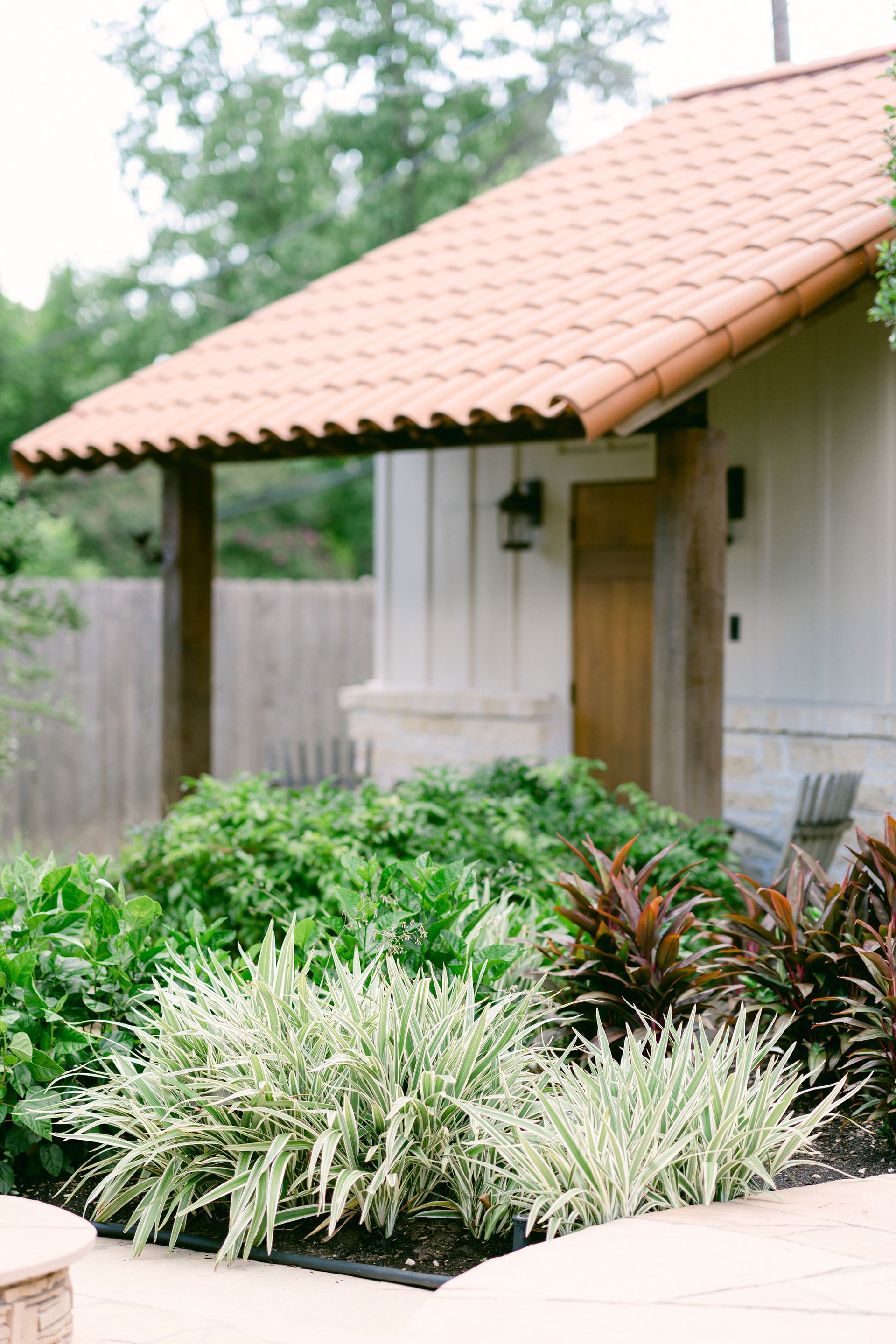 A house with a tiled roof and a lush green garden in front of it.