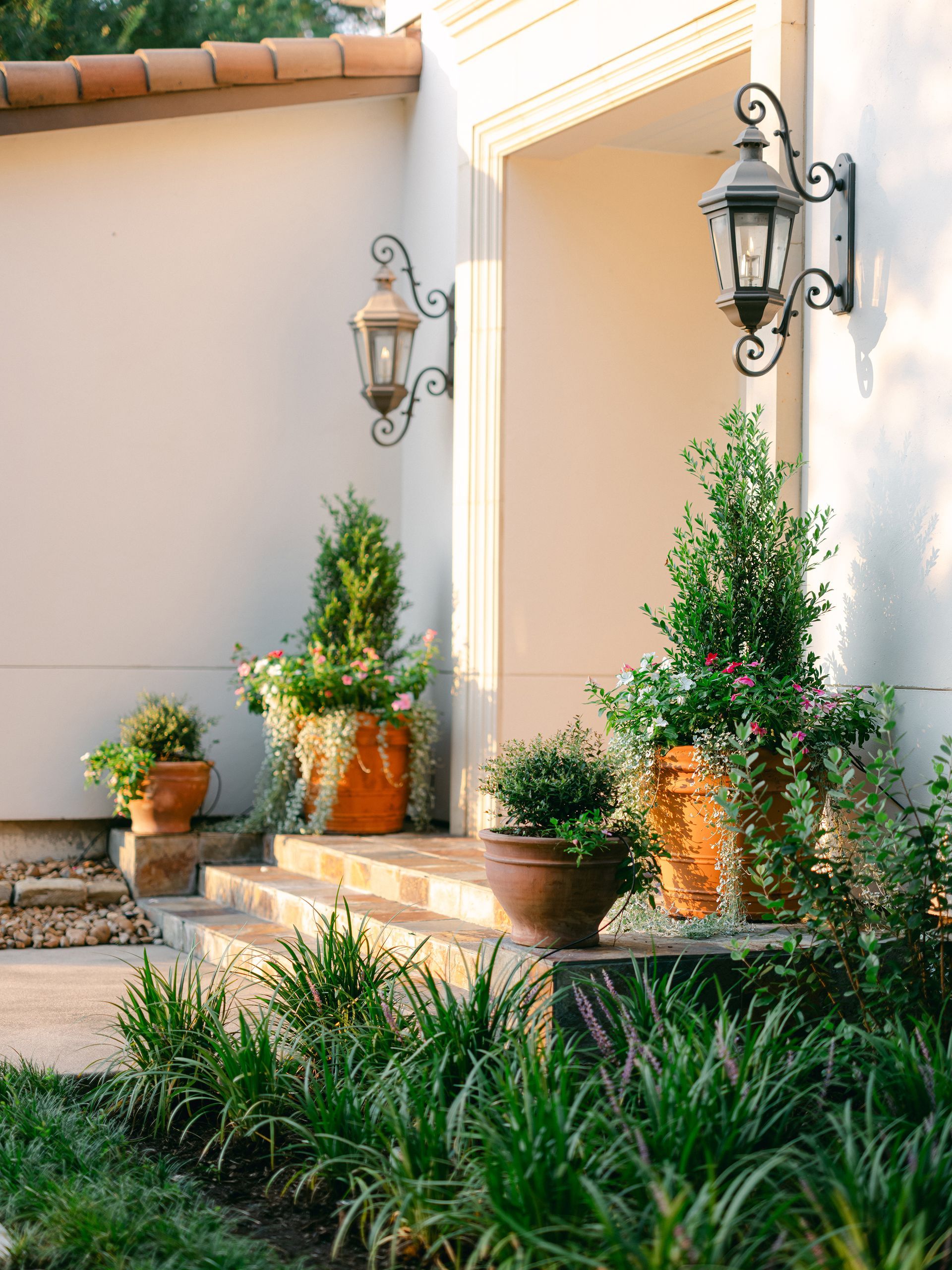 A white house with potted plants and lanterns on the steps.