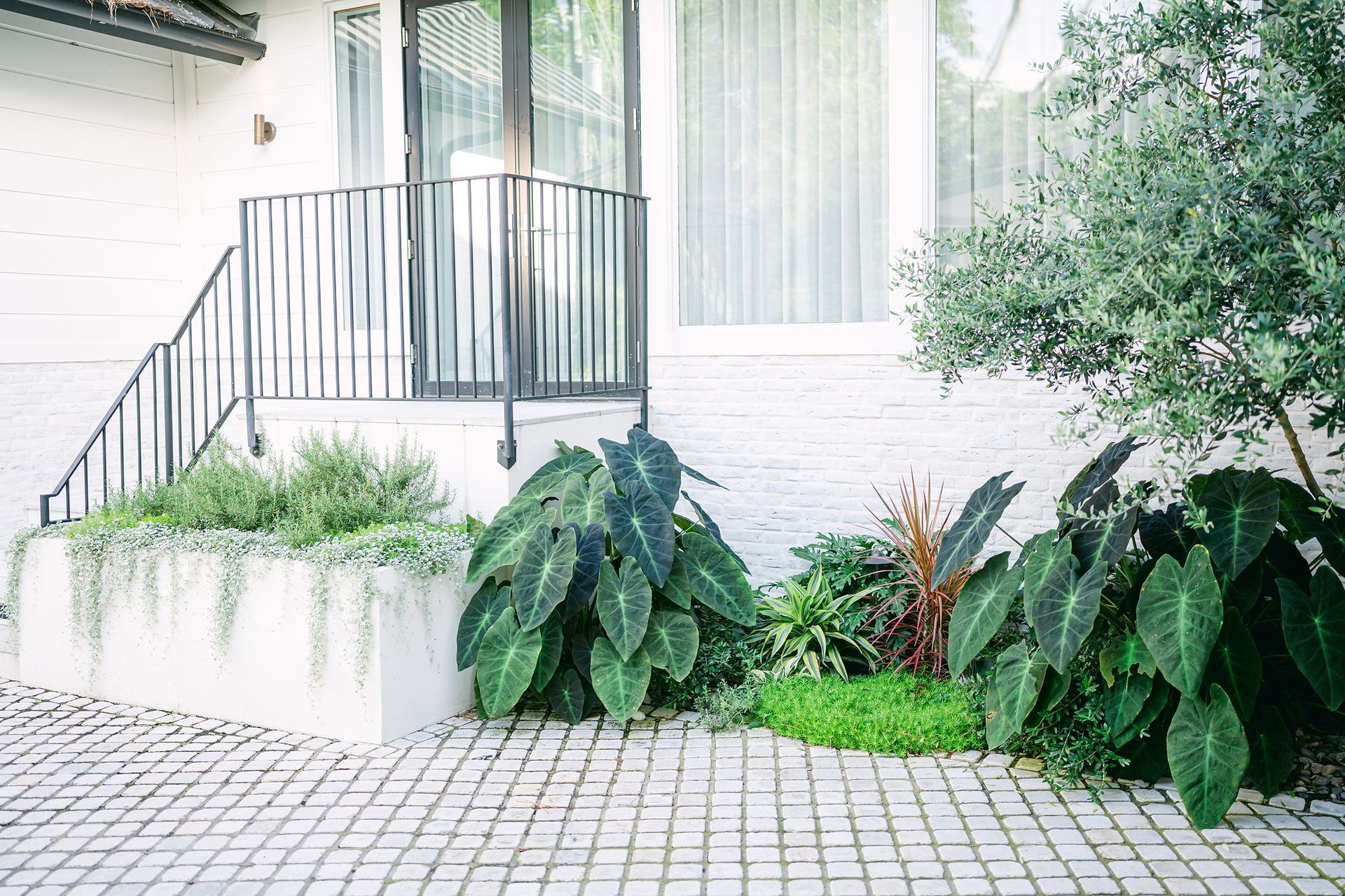 A white house with a garden in front of it.
