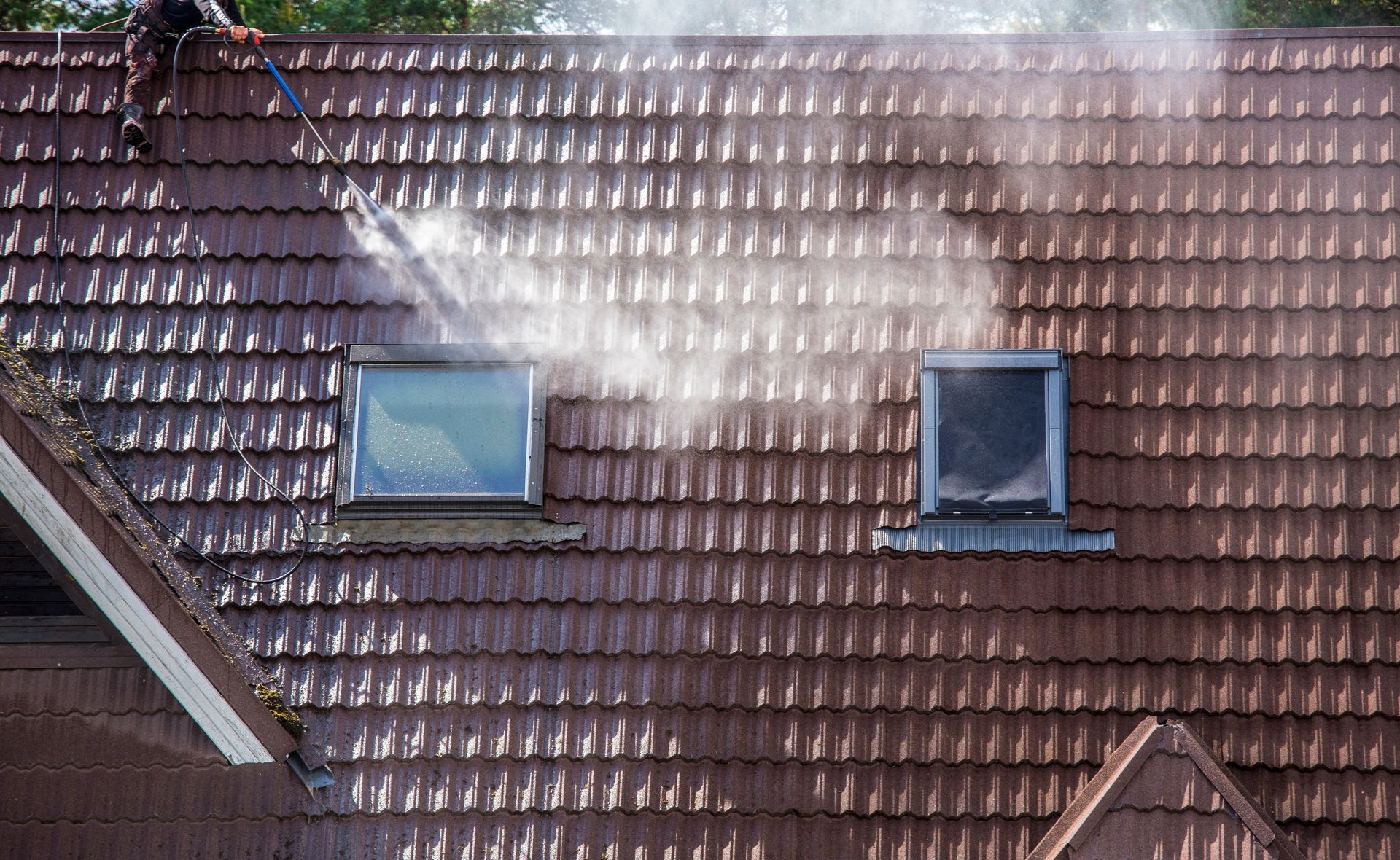 Red tiled roof with two skylights and a bright patch of reflected sunlight