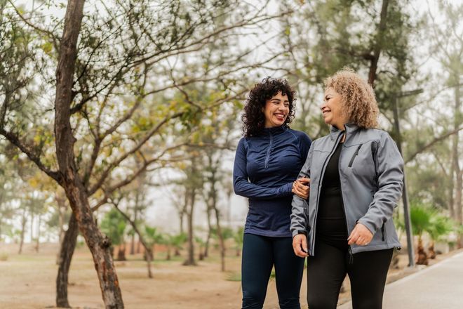 Two women are walking in a park and talking to each other.