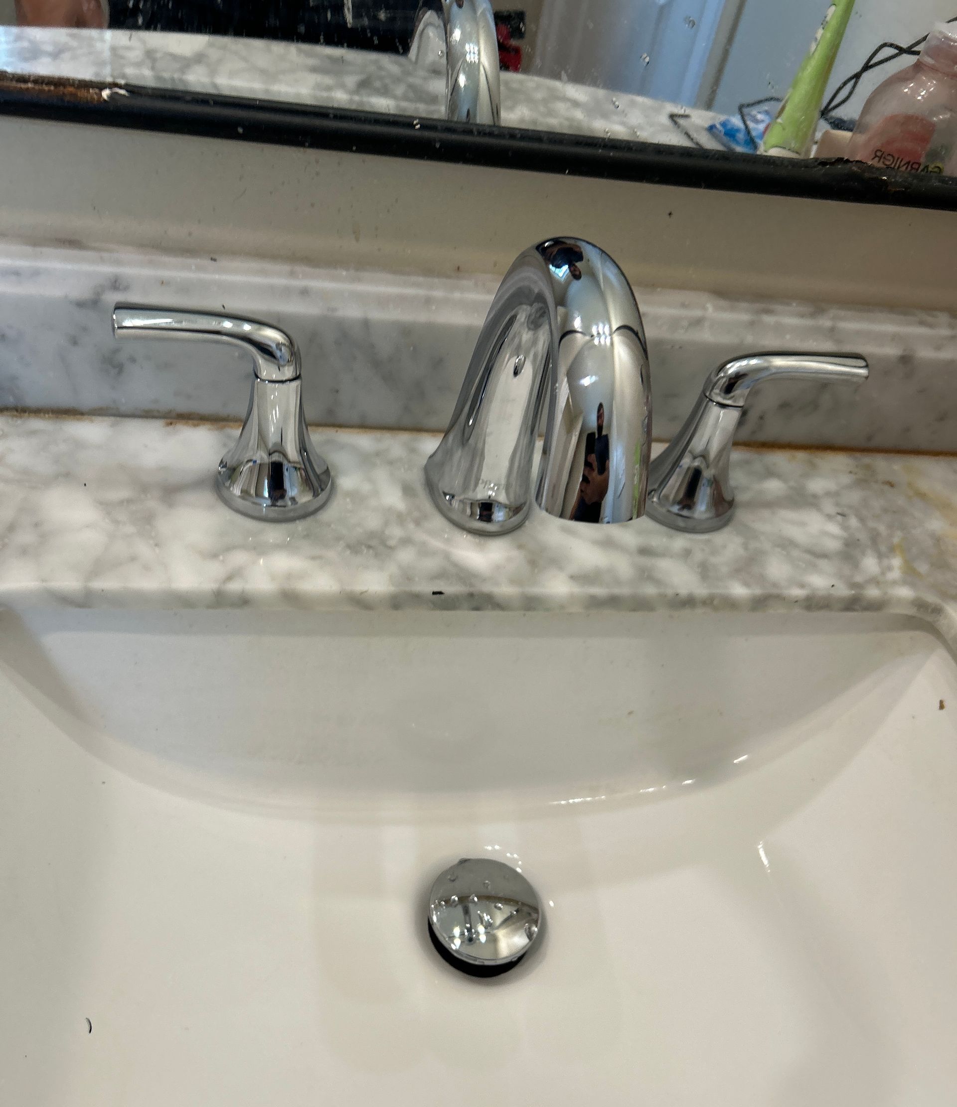 A bathroom sink with a faucet and a mirror