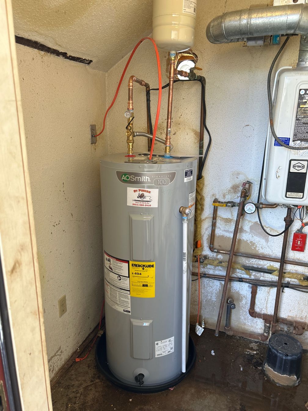 A water heater is sitting in a dirty room next to a wall.