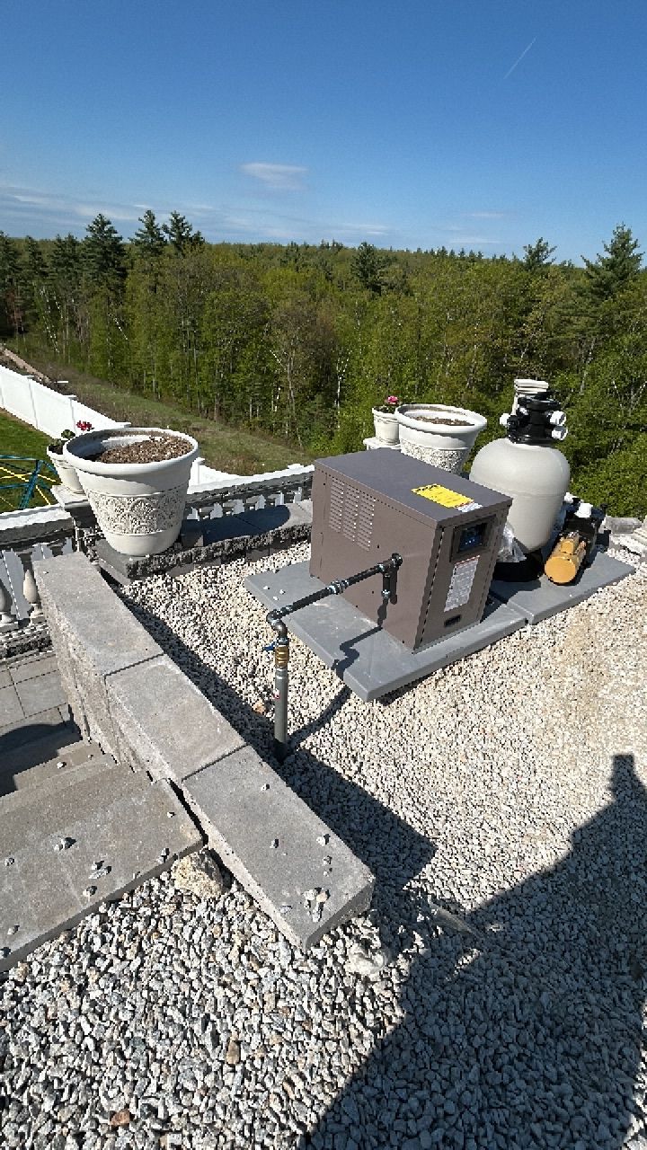 A swimming pool pump is sitting on top of a gravel roof.