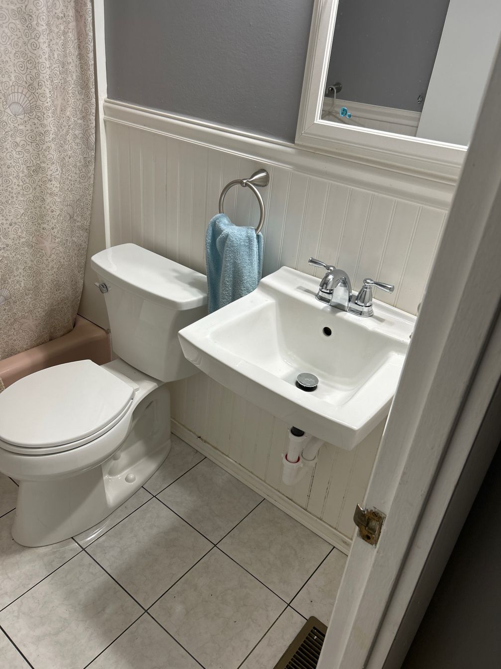 A bathroom with a toilet , sink and mirror.