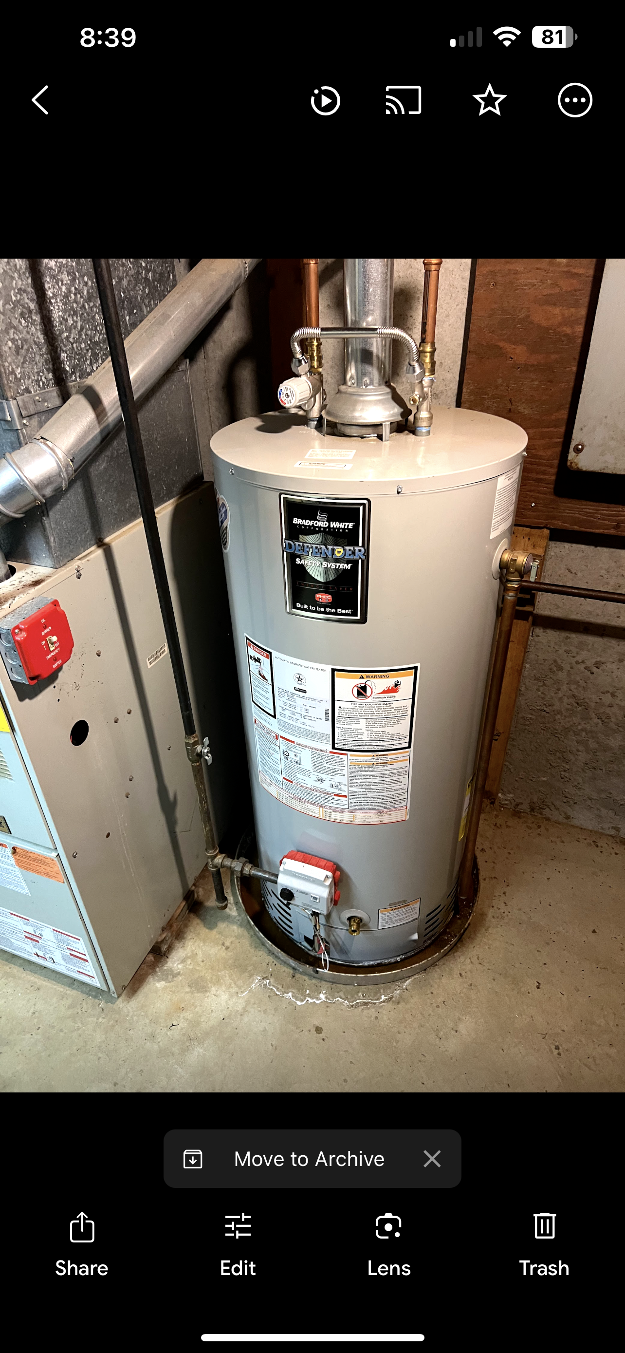 A white water heater is hanging on a wall in a bathroom.