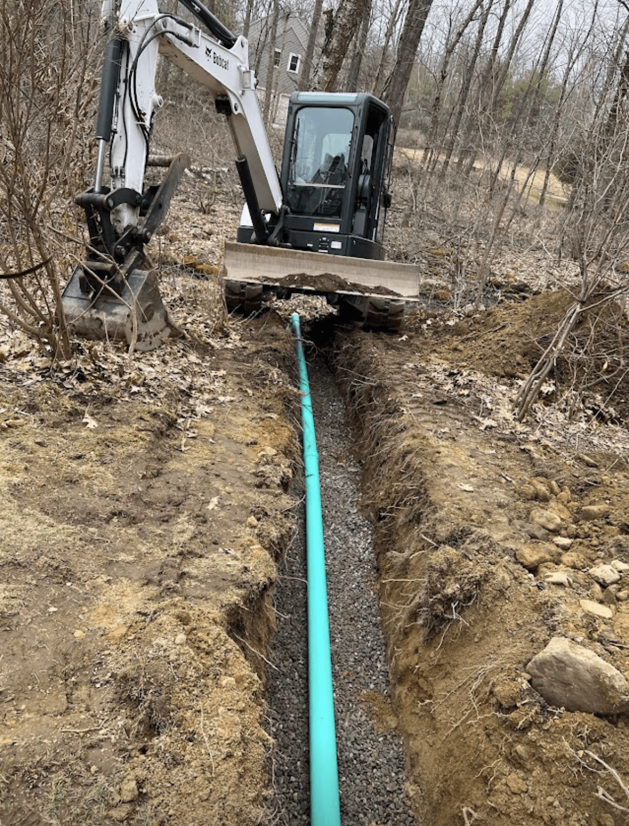 A bulldozer is digging a hole in the ground next to a green pipe.