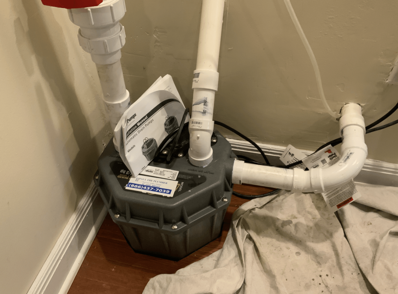 A sump pump is sitting on the floor next to a wall.