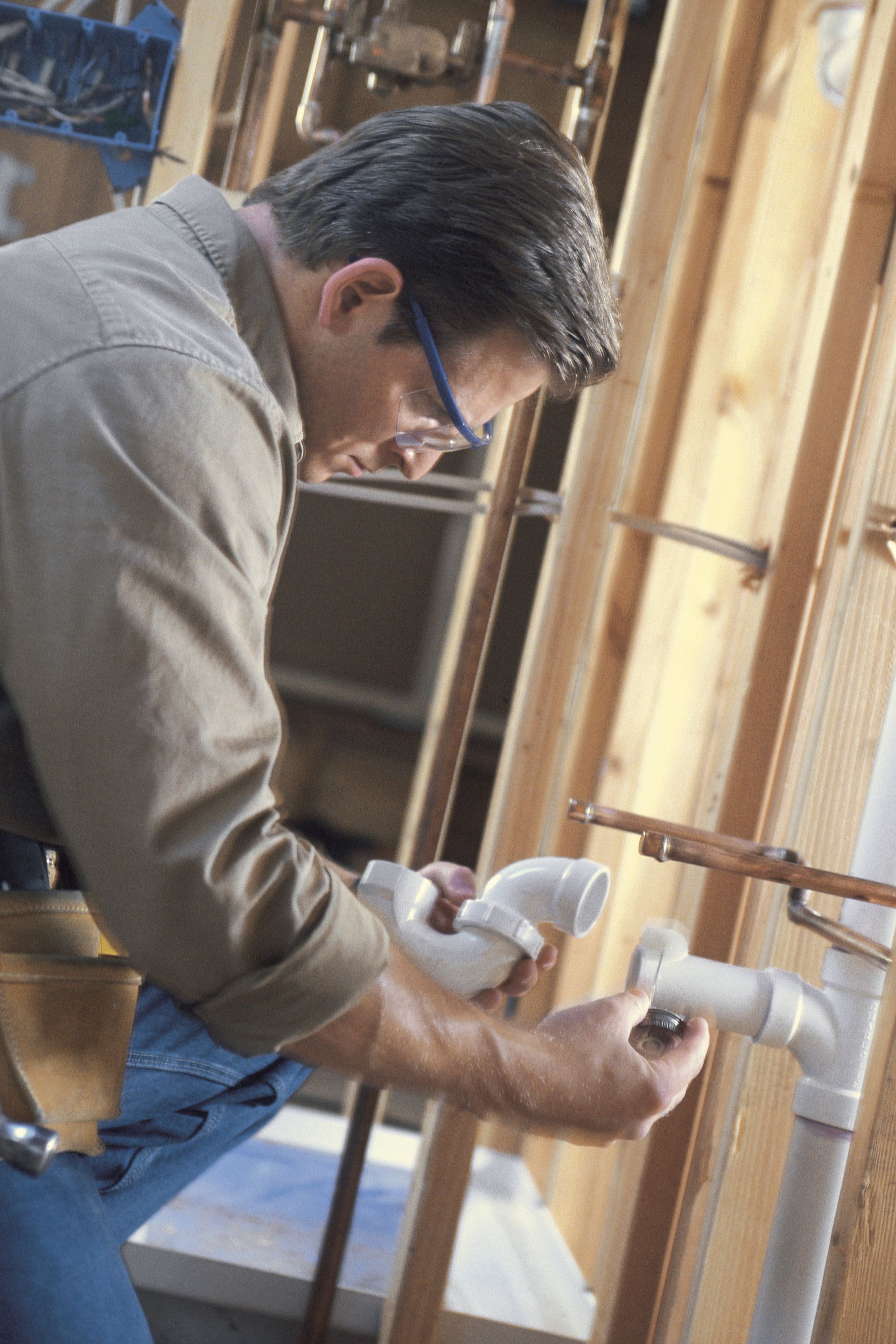 Construction workers compares two PVC connections for a plumbing pipe.