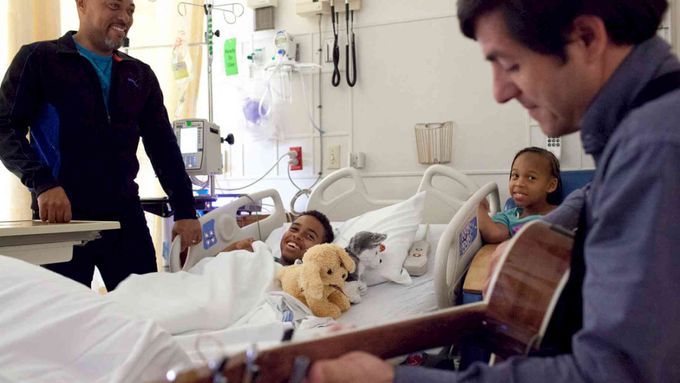 a man playing a guitart for childrens in the hospital