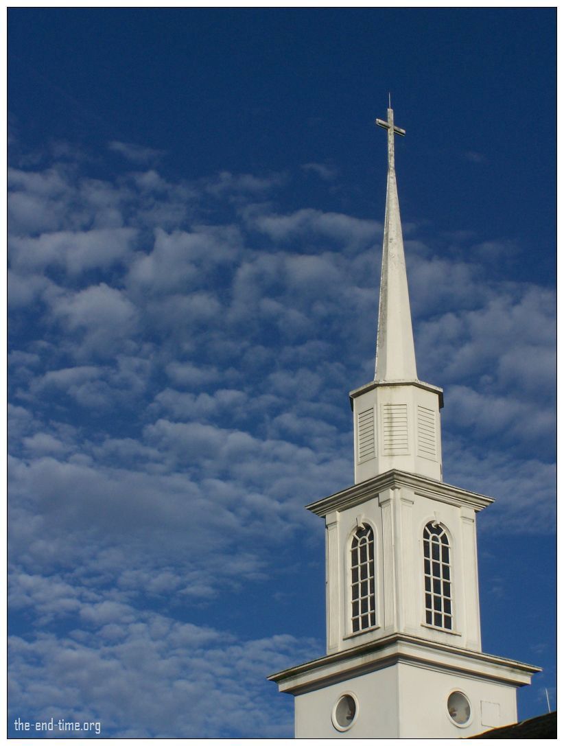 White church steeple with cross against deep blue sky.