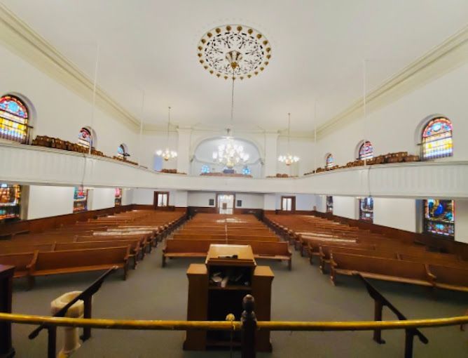 A church with rows of wooden benches and stained glass windows
