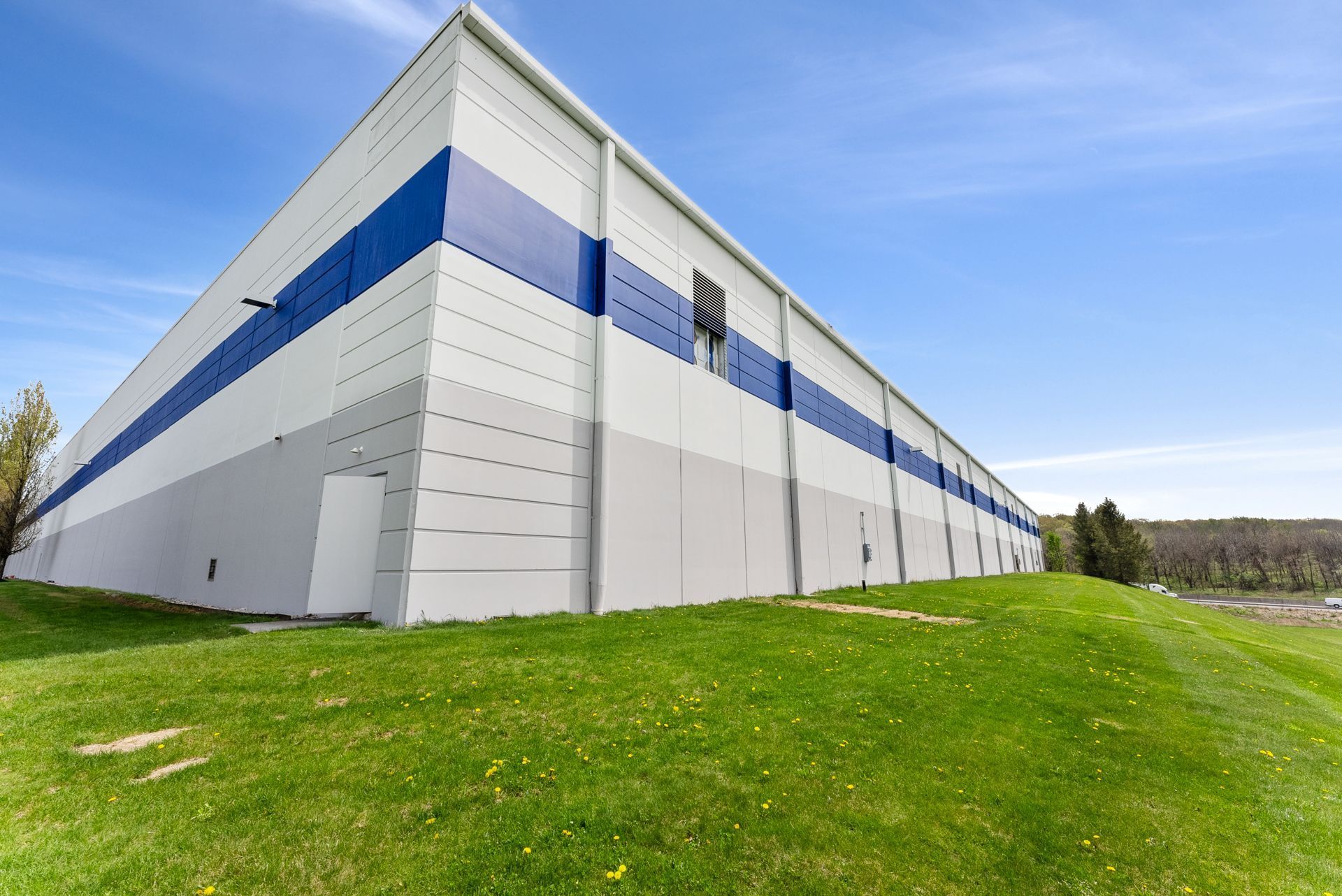 A large white and blue building is sitting on top of a grassy hill.