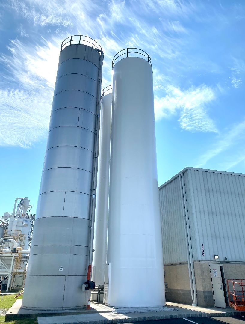 Three silos are sitting next to each other in front of a building.