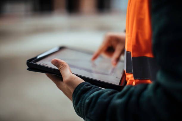 Construction project manager using digital tablet for job site coordination and scheduling.