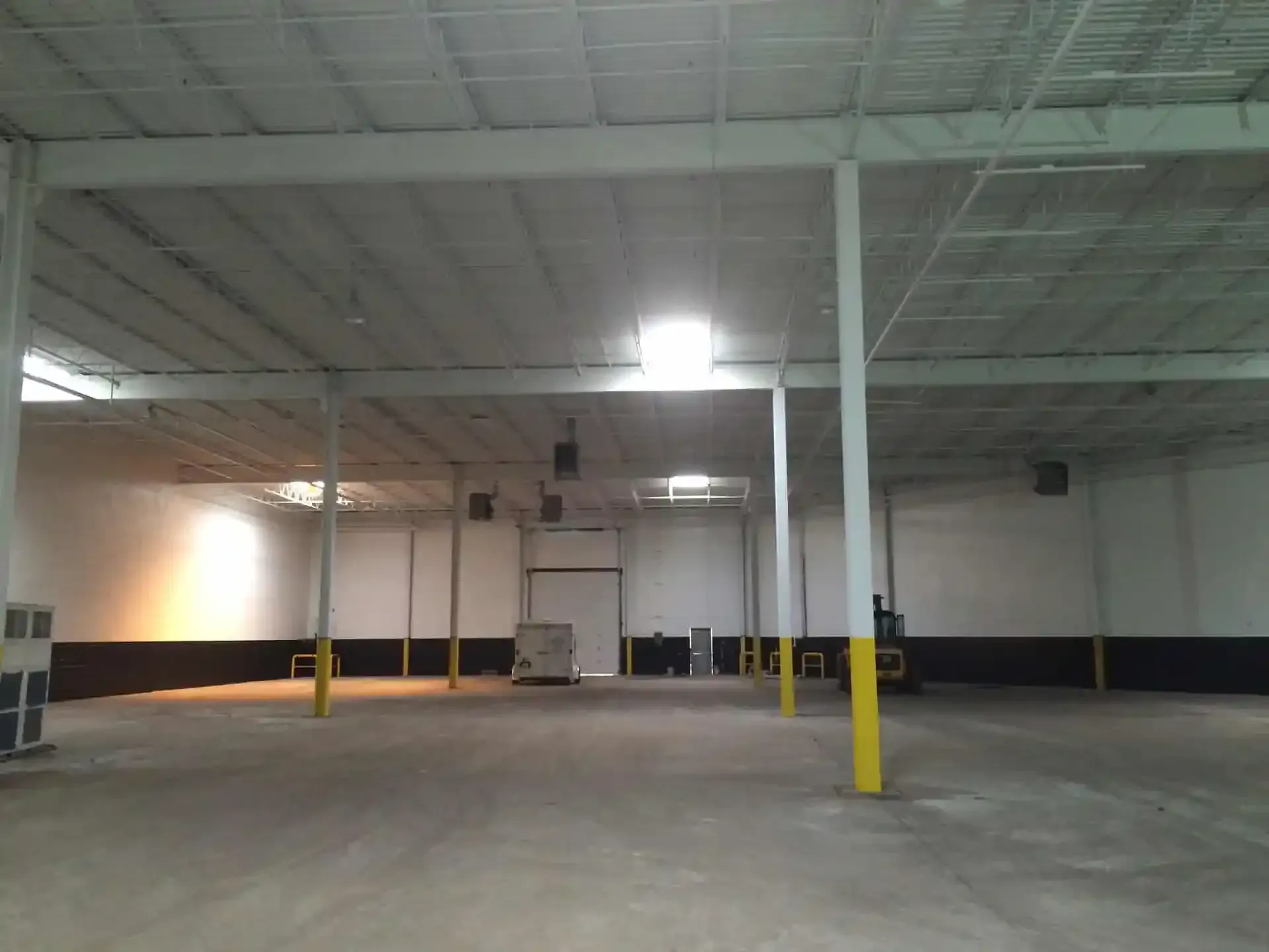 An empty warehouse with white walls and yellow poles