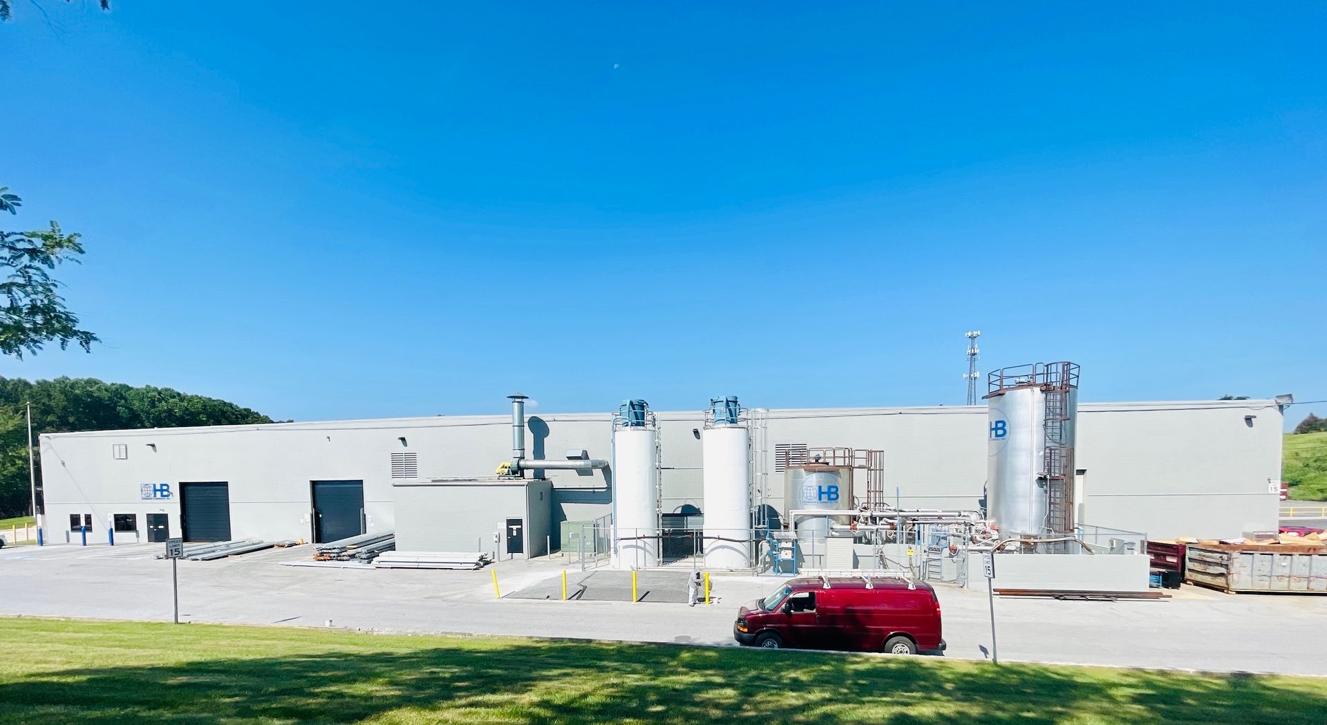 A large white building with a red van parked in front of it.