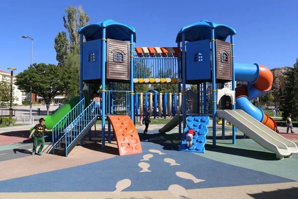 Colorful playground equipment with slides, climbing structures, and safety flooring for elementary school children