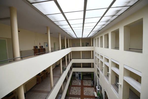 Interior atrium of school building with three levels, skylighted ceiling, white railings, and central courtyard