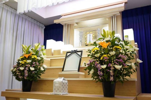 Memorial altar area with floral arrangements, wooden risers, draped curtains, and ceremonial display