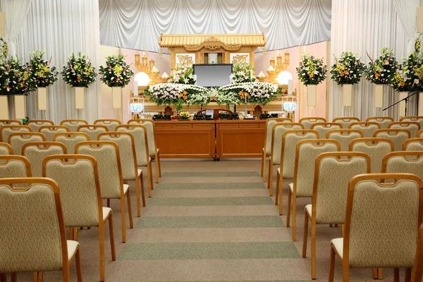 Funeral parlor seating area with ornate chairs, flower arrangements, and formal presentation space