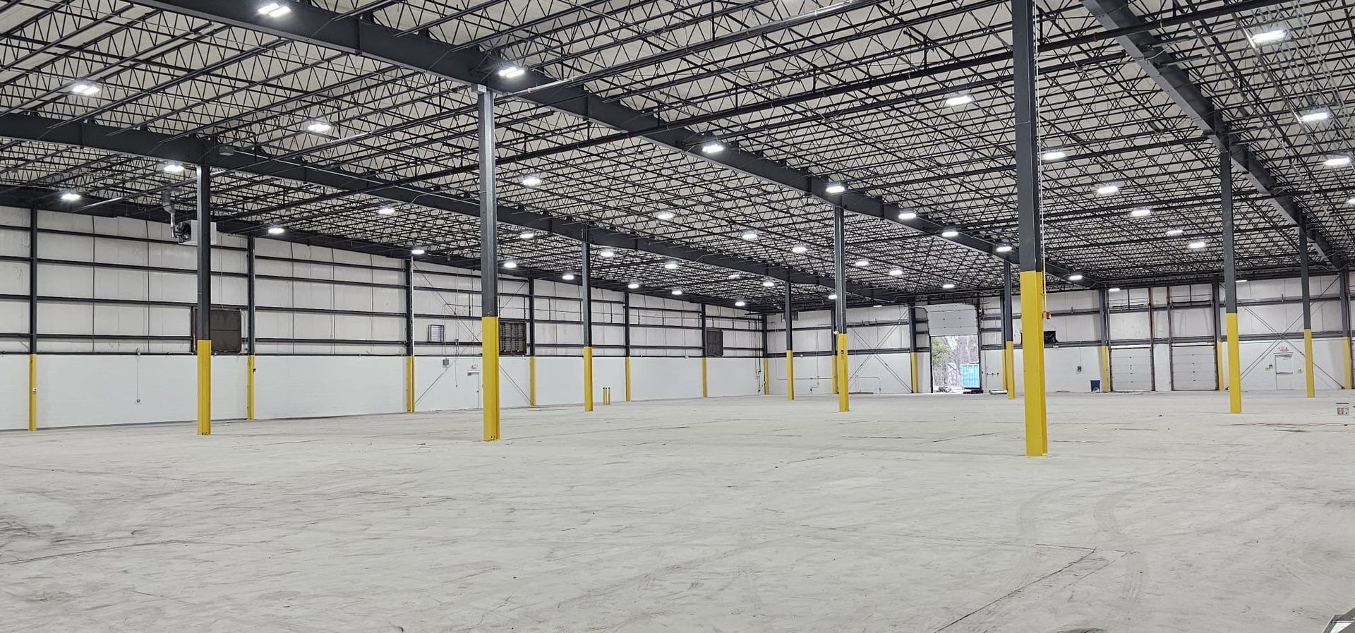 A large empty warehouse with a lot of lights on the ceiling.