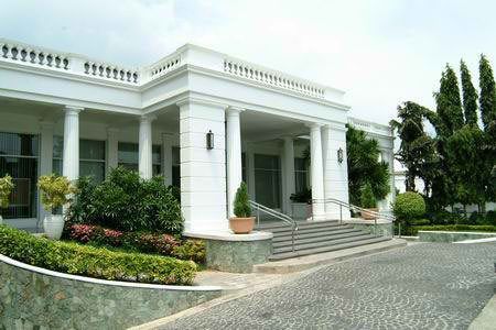 Elegant white colonial-style funeral home exterior with columns, landscaped entrance, and decorative stonework