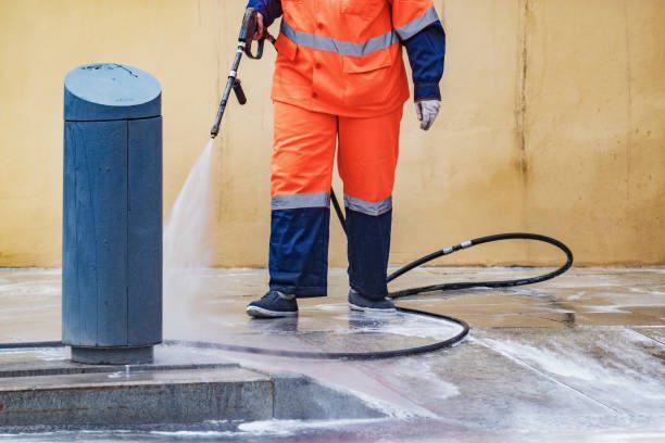 Professional cleaning commercial surface with pressure washing equipment for coating preparation.