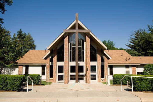 Contemporary church building with prominent wooden cross and A-frame design.