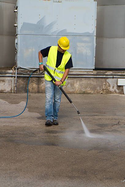 Commercial roof preparation with pressure washing before acrylic coating application process.