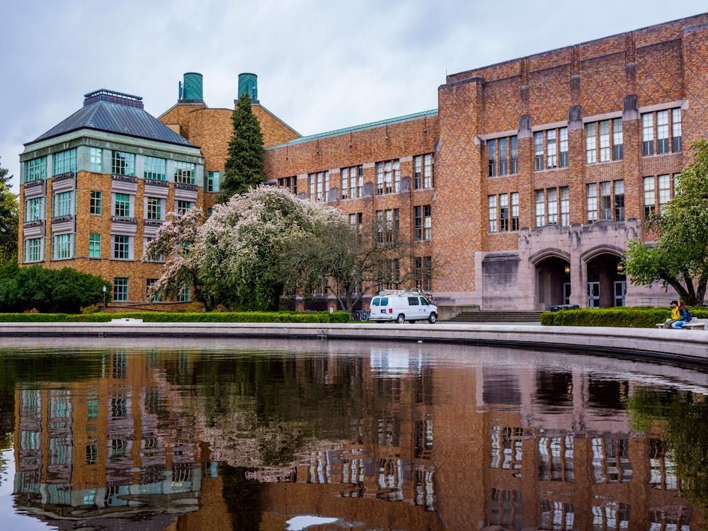 Red brick university building with reflecting pool in foreground, featuring traditional architecture and tall windows